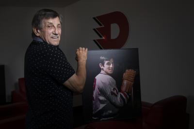 Bohuslav Štastný se svou fotografií za mlada v hokejovém, na zdi je logo Dynama